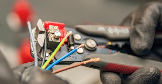 electrician's hand cutting wires